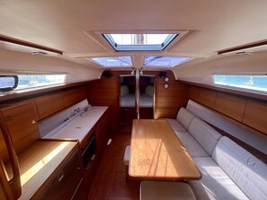 A compact interior with a central table, cushioned seating, and skylights.