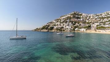 A coastal town with buildings on a hillside and sailboats on the water.