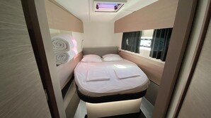 Un dormitorio pequeño con cama, ventana con cortinas, lámpara de techo y puerta.