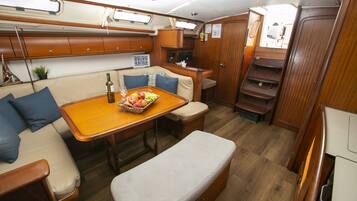 Un intérieur compact et bien éclairé, avec une table en bois, des sièges rembourrés et un petit coin cuisine.