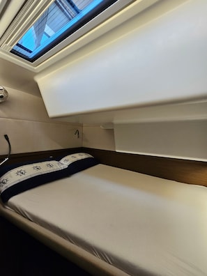A bunk bed with a skylight, a bedside table, and a pillow with a nautical design. - Sun-kissed Sailing Adventure in Split-Dalmatia, Croatia (Seget Donji)