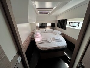 A compact, well-lit room with a bed, bedside table, and a window with curtains. - Sun-Kissed Sailing Adventure in Zadar, Croatia (Bibinje)