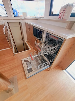 Una cocina compacta con lavavajillas, armarios de madera y ventana con vista a edificios.