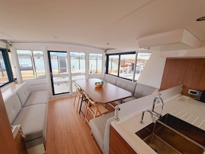 Eine kompakte Küche mit Spüle, ein Essbereich mit Tisch und Stühlen sowie eine Sitzecke mit einer Couch.