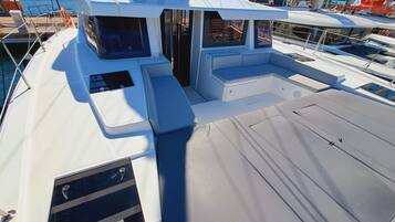 Ein Bootsdeck mit Sitzgelegenheit, einem Fenster und einem Rettungsring.