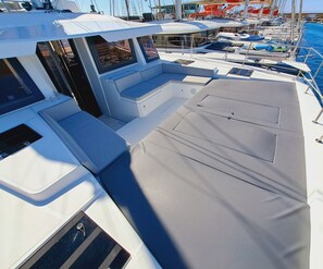A boat deck with seating areas, windows, and a covered section.