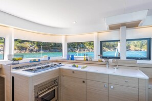 Eine moderne Küche mit Einbauofen, Gaskochfeld und großem Fenster mit Meerblick.