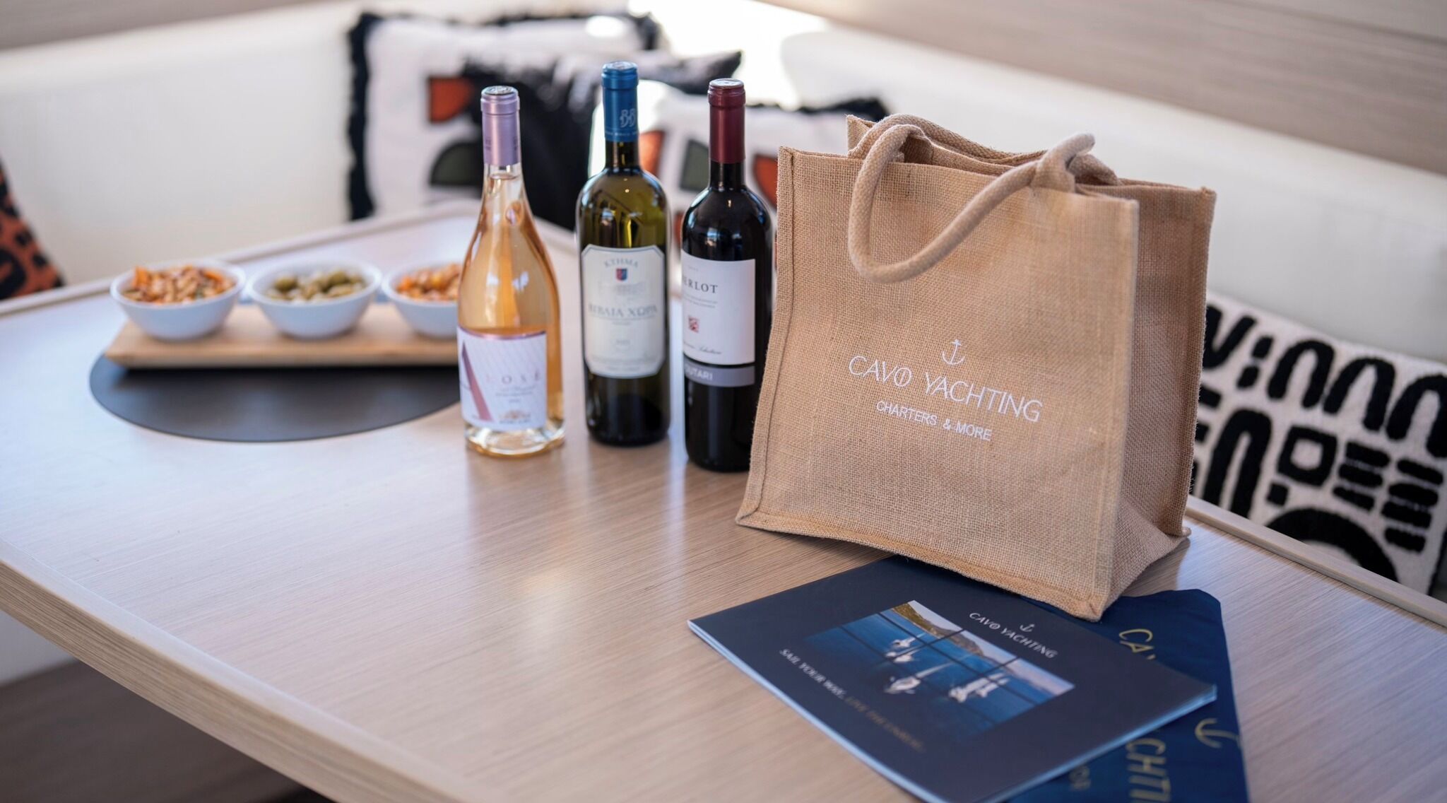 Uma mesa com garrafas de vinho, um saco de papel castanho e um folheto.