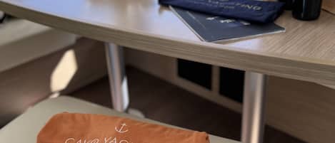 A table with a bowl of fruit, bottles of wine, a book, and towels with text.