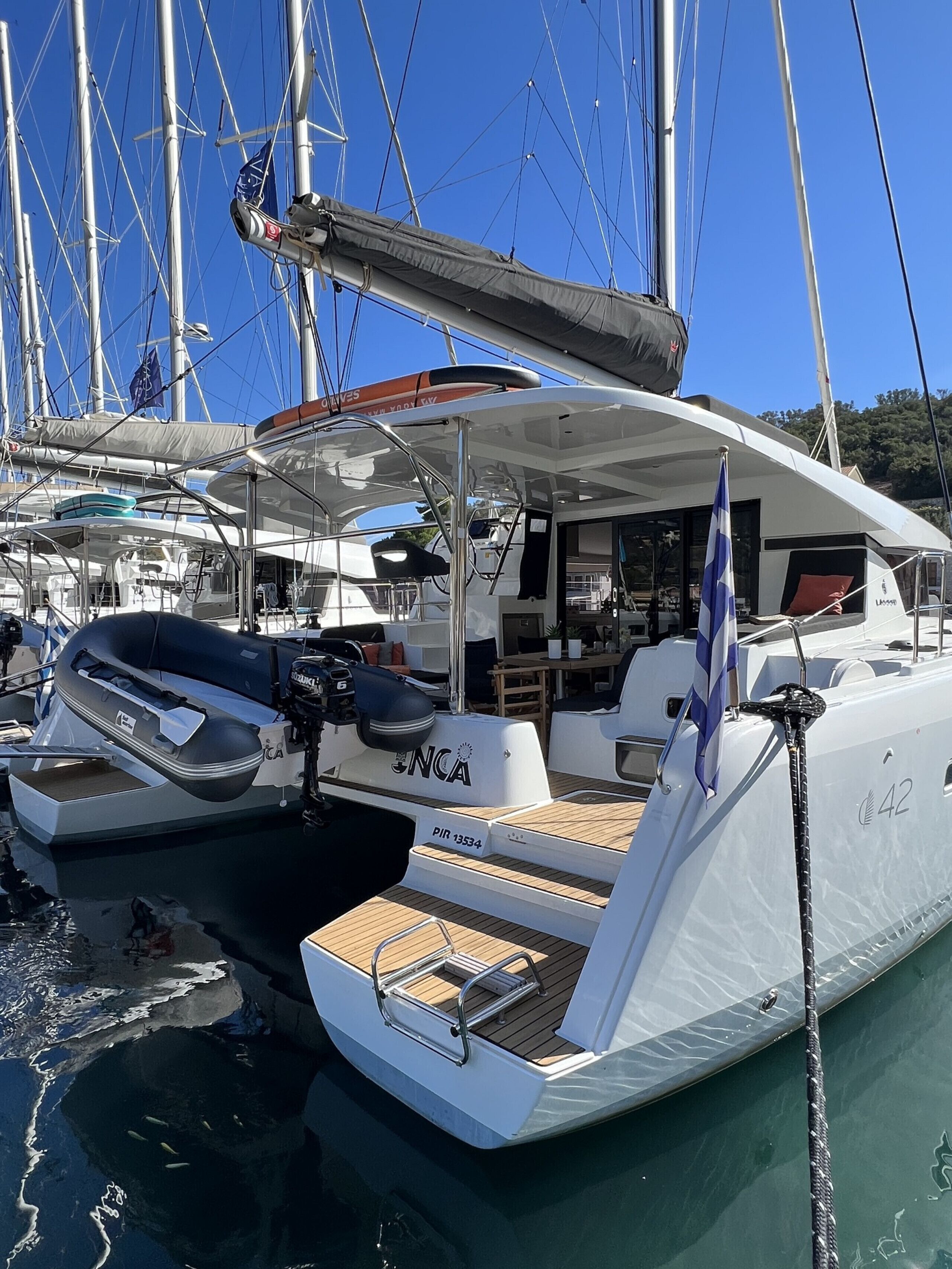 A yacht docked at a marina with a covered deck, seating area, and a visible flag.