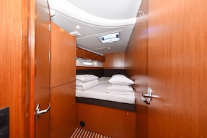 Ein kleiner, gut beleuchteter Aufenthaltsraum mit einem Bett, einem Fenster und einer Tür.