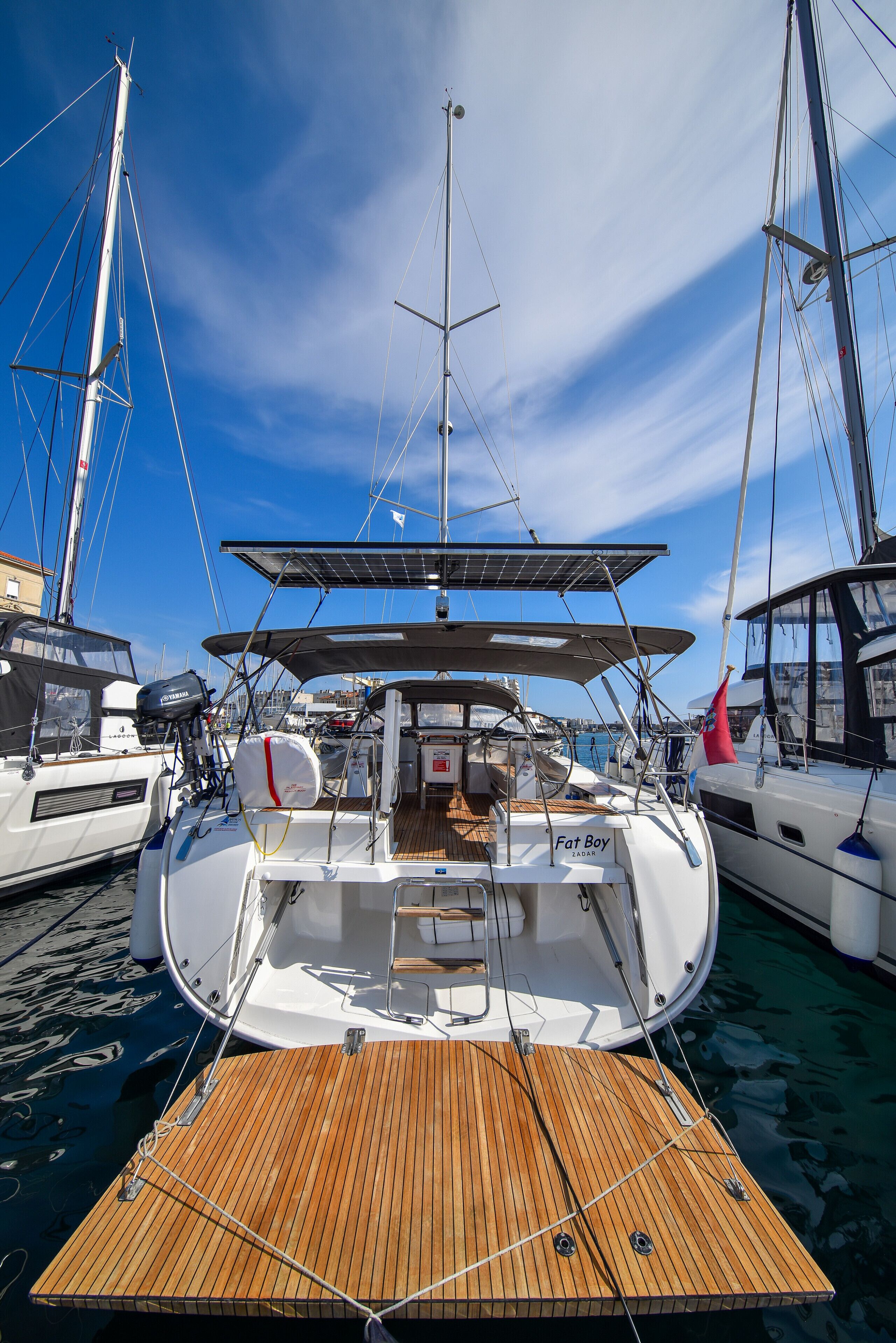 A sailboat docked at a marina with a wooden deck, a mast, and a cabin.