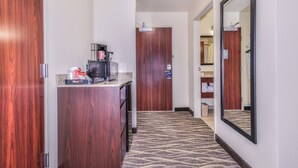 A hotel hallway with a coffee station, a wooden door, and a mirror on the wall. - Cobblestone Hotel & Suites - Montevallo (Montevallo)