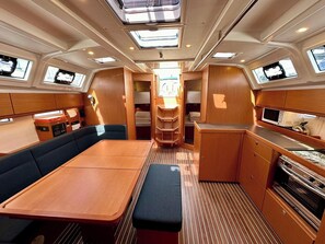 A compact interior with a dining area, seating, a kitchenette, and a small bathroom. - Sun-Kissed Sailing Adventure in Zadar, Croatia (Bibinje)