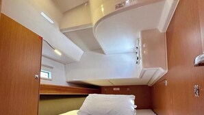 Une petite cabine comprenant un lit, un petit coin salon et un placard de rangement.
