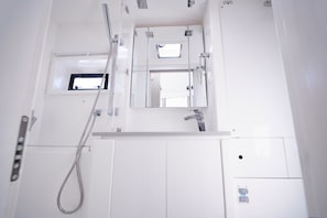 Ein Badezimmer mit Dusche, Spiegel und Fenster.
