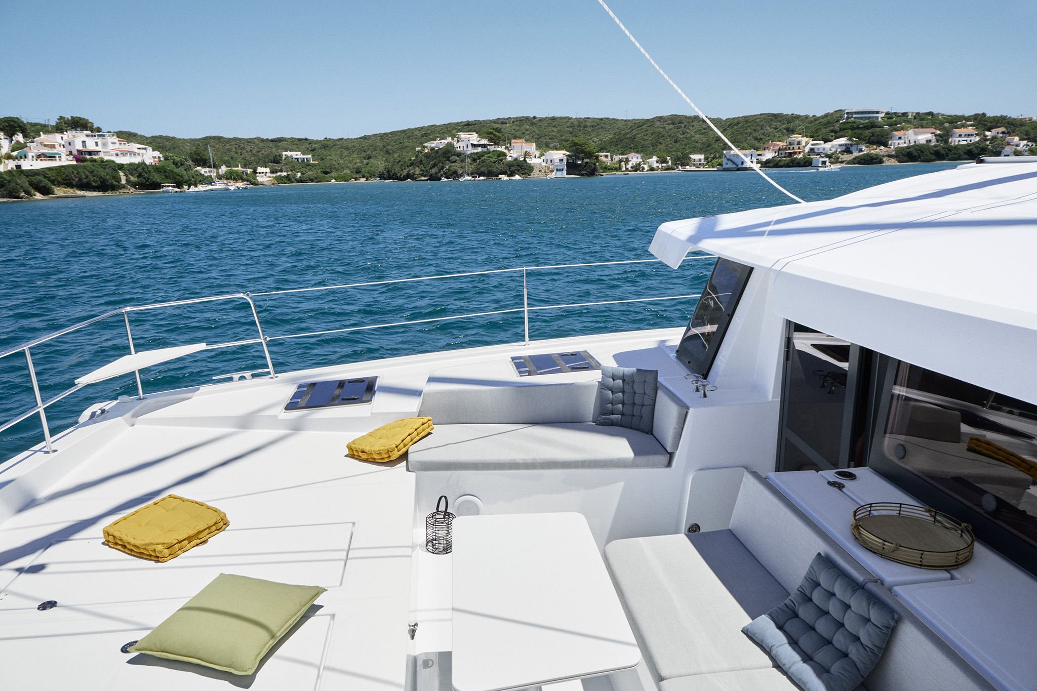 A yacht with a white deck, cushioned seating, and a small table.