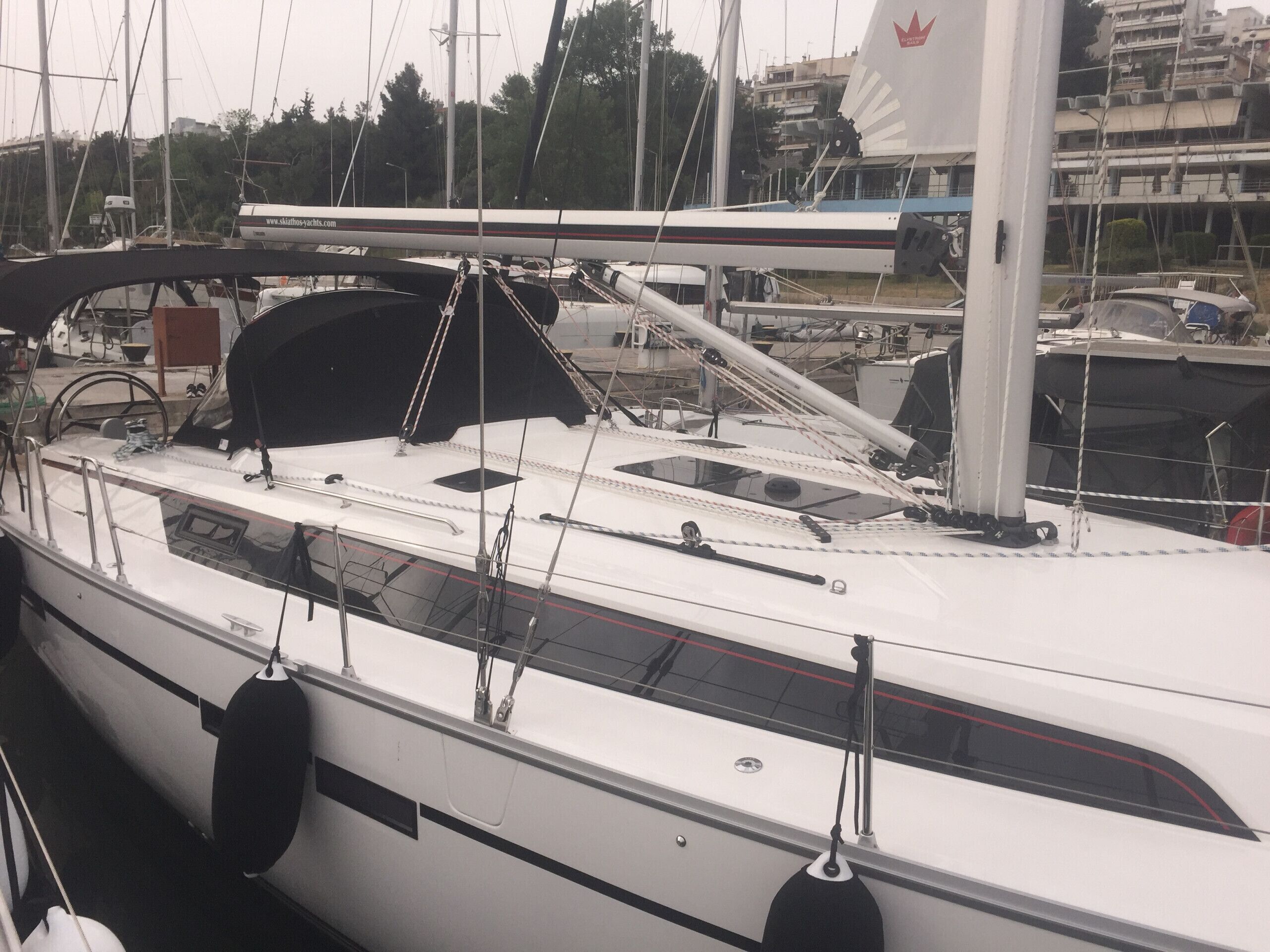 A sailboat docked at a marina with visible rigging and a cabin structure.