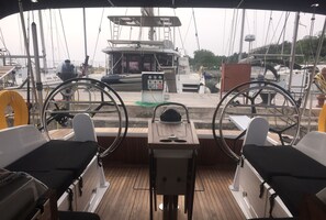 A boat's deck with two steering wheels, a control panel, and a view of the marina. - Sun-Kissed Sailing Adventure in Islas Esporadas (Skiathos)