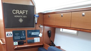 A cabin interior with a blue upholstered seat, control panels, and a sign reading 'CRAFT ADRIATIC SEA'.