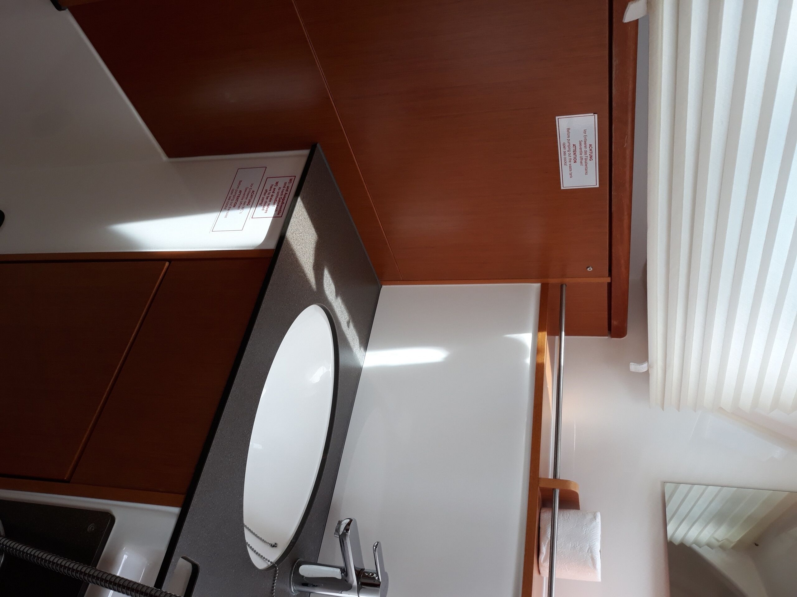 A bathroom with a white sink, a mirror, and a wooden cabinet.