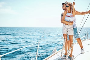 Un couple à bord d’un voilier, avec l’océan en arrière-plan.