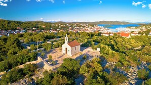 Una iglesia pequeña rodeada de árboles y un pueblo costero.