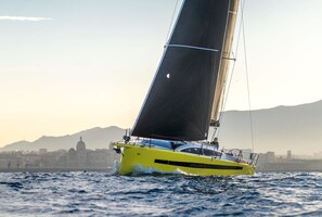 A sailboat with a yellow hull and black sails on the water.
