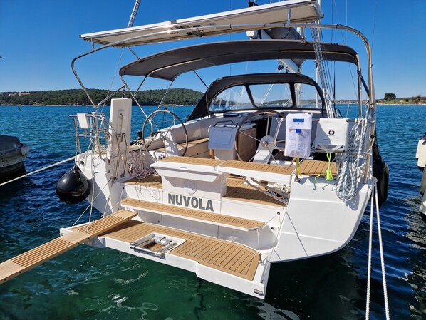 Ein Boot namens NUVOLE mit überdachtem Deck, Steuer und einer kleinen Sitzecke.