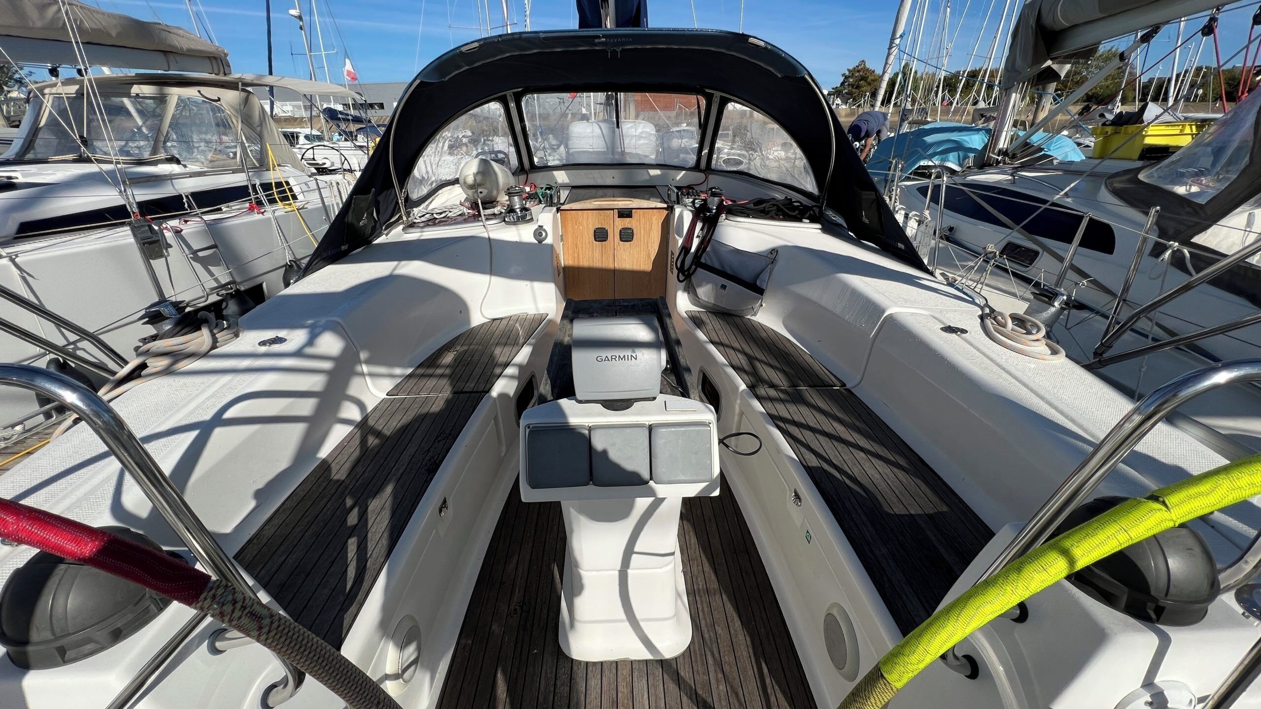 Le pont d’un bateau, équipé d’un appareil de navigation Garmin, d’un plancher en bois et de rambardes métalliques.