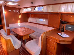 Een ruimtelijk bootinterieur met een eethoek, zitplaatsen en een kleine bar.