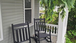 A porch with two black rocking chairs, a white railing, and a window with blinds. - Short Walk to Track & Broadway, SPAC Close Too! (Saratoga Springs)