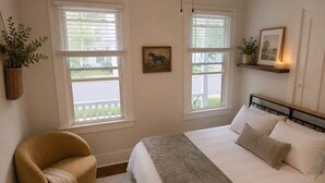 A bedroom with a bed, a chair, a window, and a wall-mounted shelf. - Short Walk to Track & Broadway, SPAC Close Too! (Saratoga Springs)