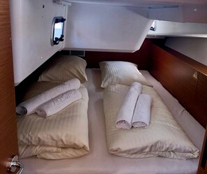 A compact cabin with two beds, each with a rolled towel and a pillow.