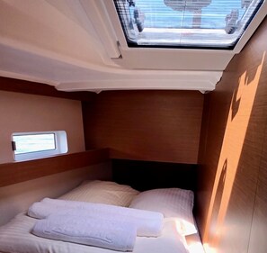 A compact room with a bed, a small window, and a skylight.