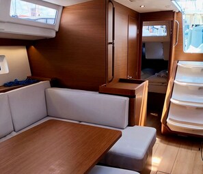 A compact interior with a wooden table, cushioned seating, and a small kitchenette.