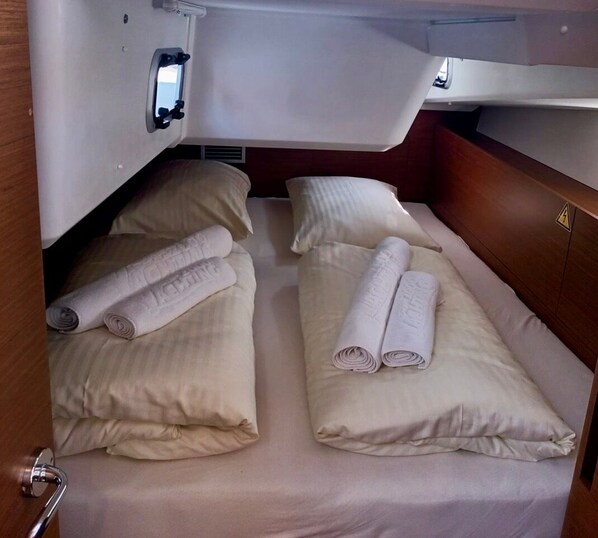 Une cabine compacte équipée de deux lits, chacun agrémenté de serviettes et d’oreillers pliés.