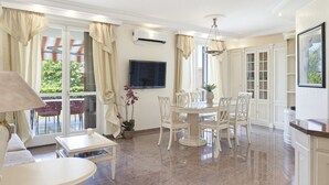 Amplia sala de estar con una mesa de comedor, sillas, un televisor y una planta en maceta.