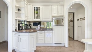 Cocina con muebles blancos, horno empotrado y encimera de granito.