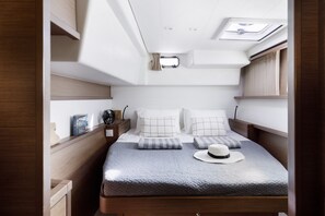 A compact, well-lit room with a bed, a small table, and a window with curtains. - Sun-Kissed Sailing Adventure in the Dodecanese Islands (Rodos)