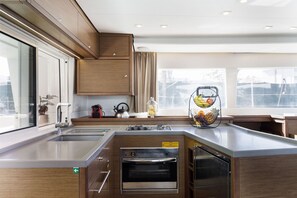 A modern kitchen with a built-in oven, a sink, and a window with a view of the outside. - Sun-Kissed Sailing Adventure in the Dodecanese Islands (Rodos)