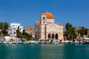Una iglesia costera con una cúpula destacada, junto a un puerto deportivo con barcos.