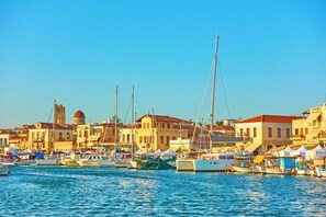 Un port de plaisance avec des bateaux amarrés, des bâtiments aux toits rouges et une tour imposante.