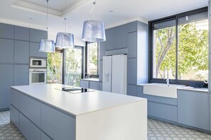 Eine moderne Küche mit einer großen Kochinsel, eingebauten Geräten und großen Fenstern.