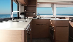 Une petite cuisine fonctionnelle avec un évier en acier inoxydable, une bouilloire et des meubles de rangement en bois.