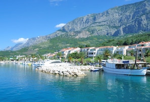 A coastal marina with boats, a rocky breakwater, and buildings with red roofs. - Sun-Kissed Sailing Adventure in Split-Dalmacia, Croatia (Tucepi)