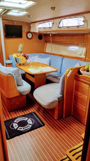 A compact interior with a dining table, two chairs, a small sofa, a TV, and a window. - Sun-Kissed Sailing Adventure in Split-Dalmacia, Croatia (Tucepi)