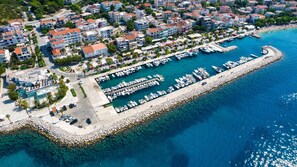 An aerial view of a coastal marina with boats docked, a promenade, and residential buildings. - Sun-Kissed Sailing Adventure in Split-Dalmacia, Croatia (Tucepi)