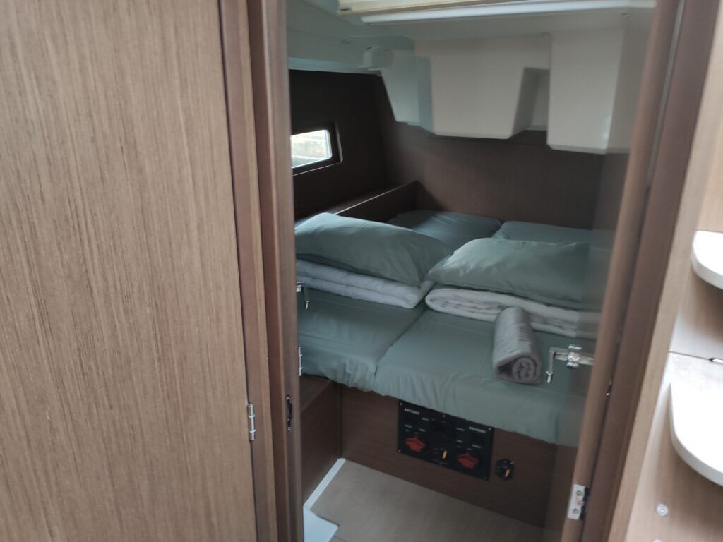 Un intérieur de camping-car compact comprenant un lit, une petite fenêtre et un panneau de commande.