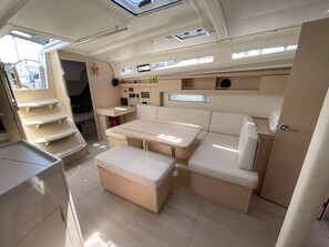 A compact, well-lit interior with a dining area, seating, and storage compartments. - Sun-Kissed Sailing Adventure in Islas Sarónicas (Alimos)